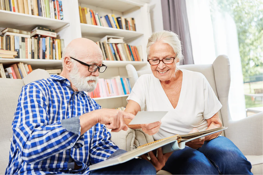 Senior couple looking through family photos together while receiving personalised Home Care Support Services in a comfortable home environment.