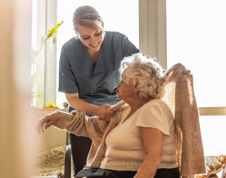 Support worker assisting a senior woman with dressing as part of professional Home Care Support Services that enhance safety, dignity, and wellbeing.