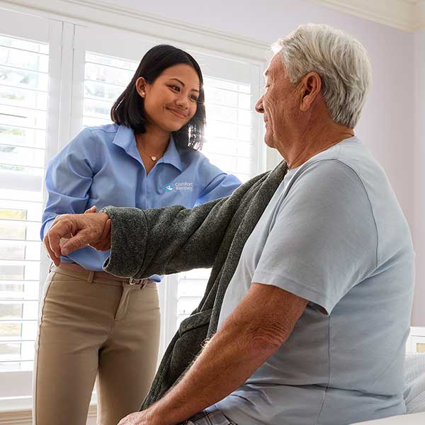 Care worker helping an older man with mobility exercises through reliable Home Care Support Services designed to support independent living.